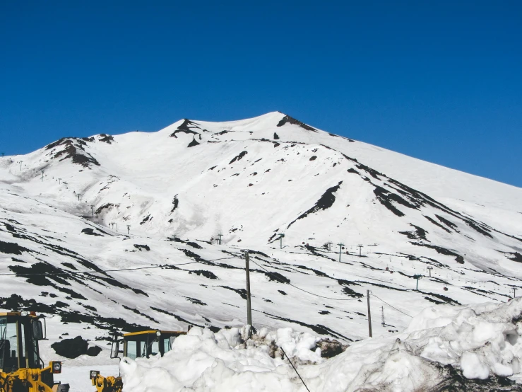 a bulldozer digging snow in front of a mountain