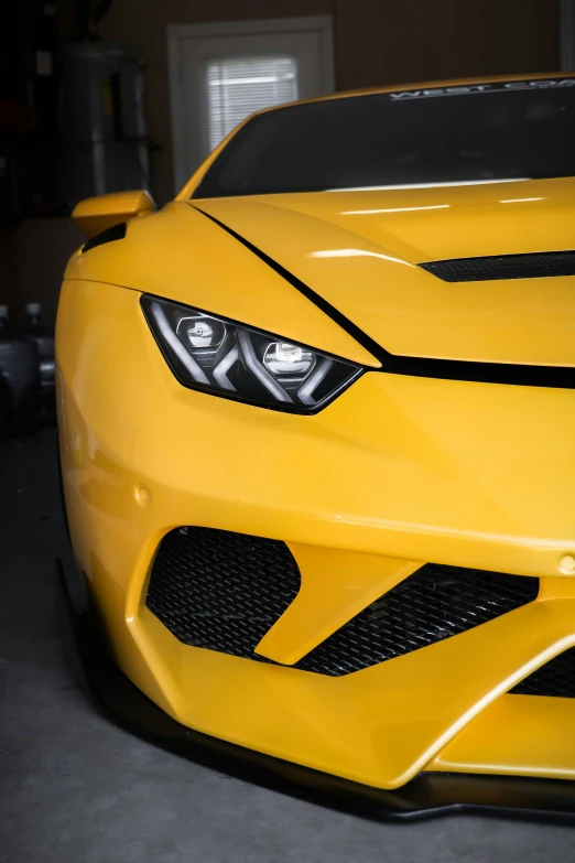 the front of a yellow sports car that has been painted with black stripes