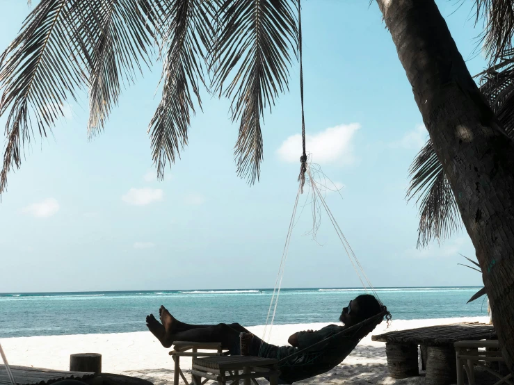 man relaxing in hammock on the beach with his feet on the edge