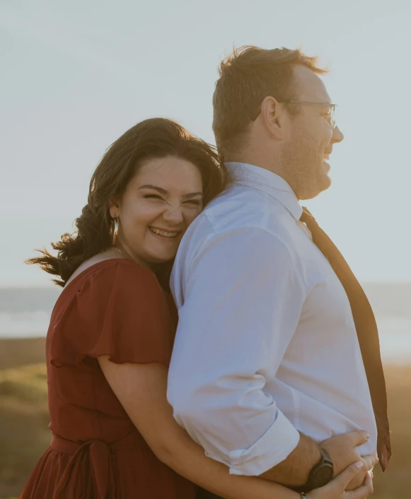 an engaged couple standing in front of the ocean