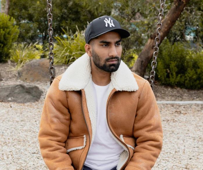 a man in a leather jacket is sitting on a swing