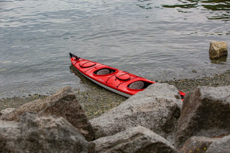 a red kayak that is sitting on the shore