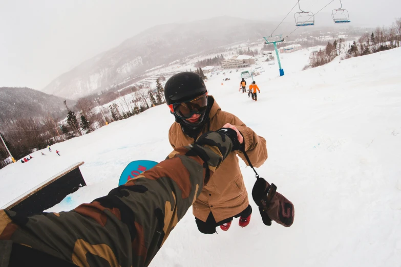 a person wearing sunglasses holding a snowboard on a snowy hill