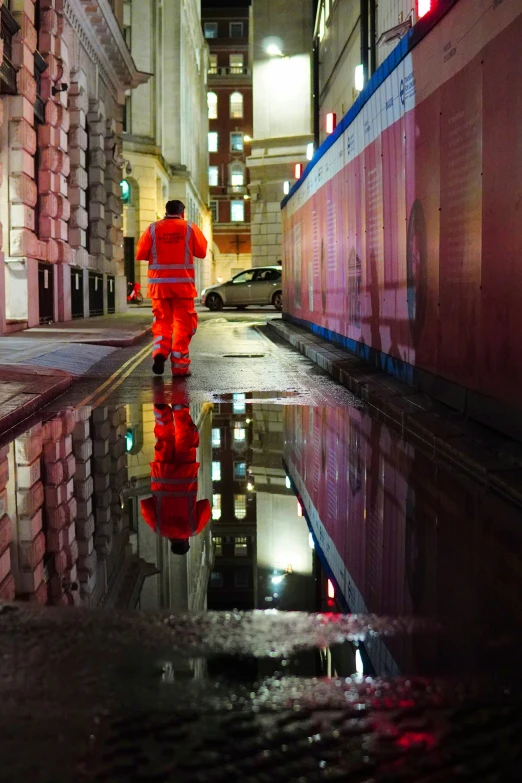 a person walking down a wet city street at night