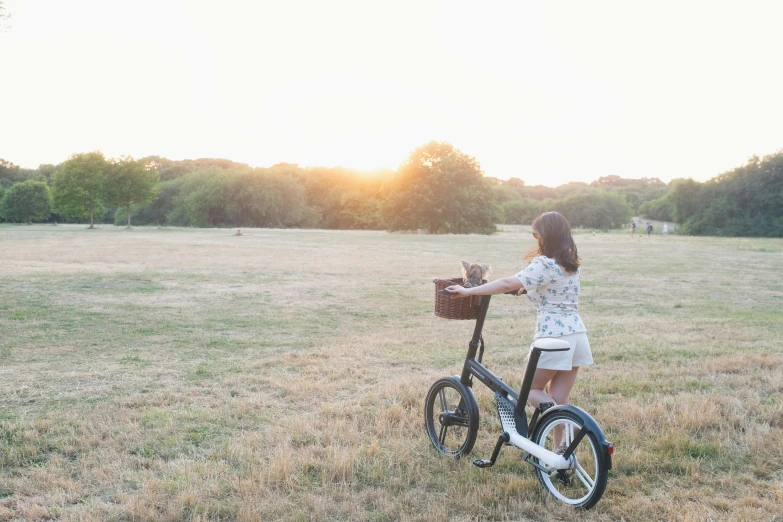 a woman holding a dog in a basket on a bicycle