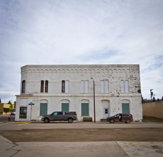 a large old building with two cars parked in front of it