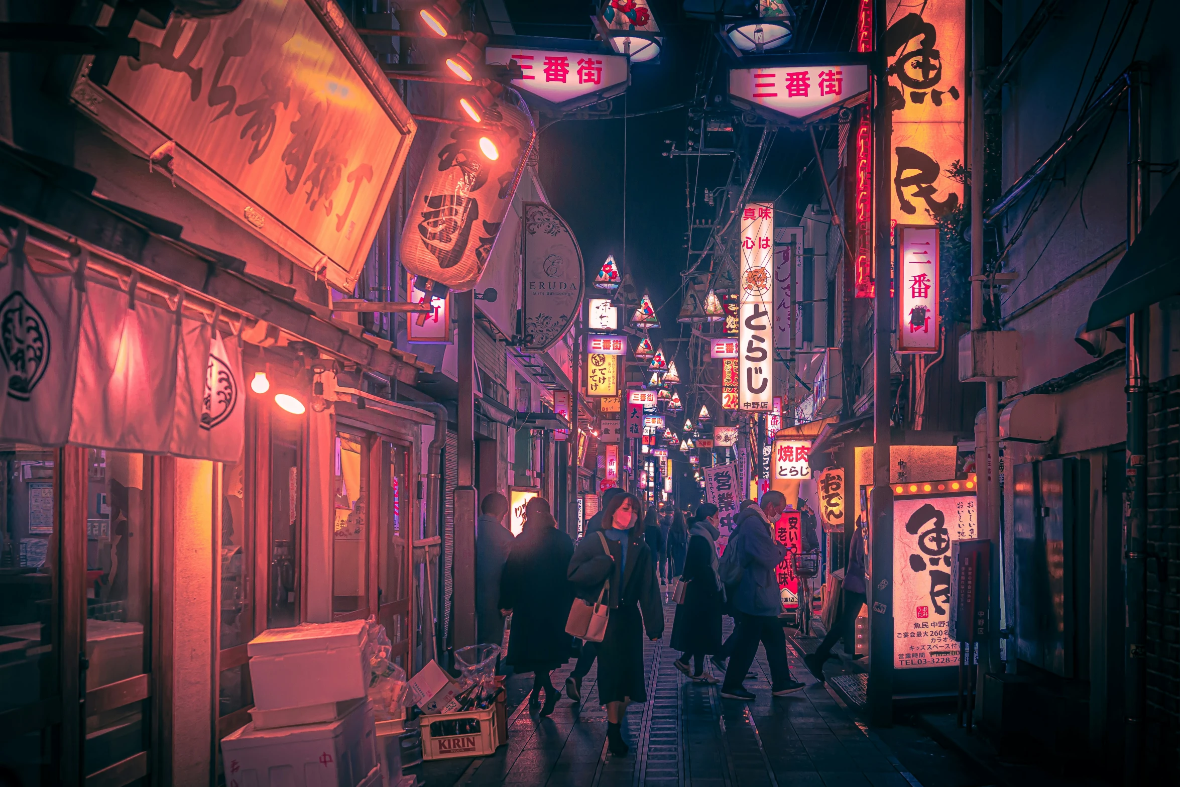 people walking down an oriental street lit up by neon lights