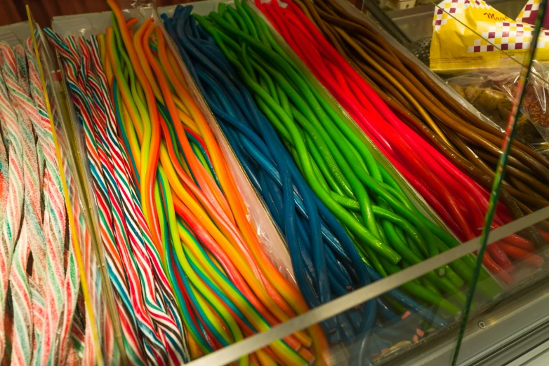 various colored lolly pop noodles sitting in a glass bin