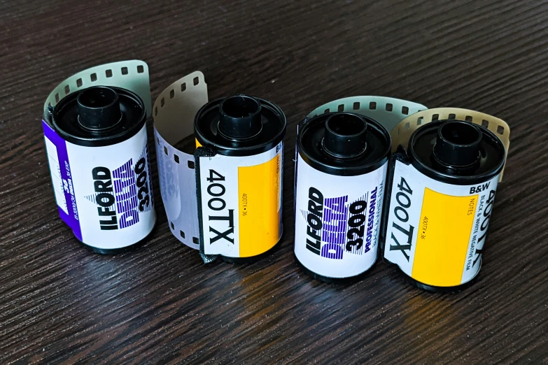 four batteries of different colors are sitting on a wooden table