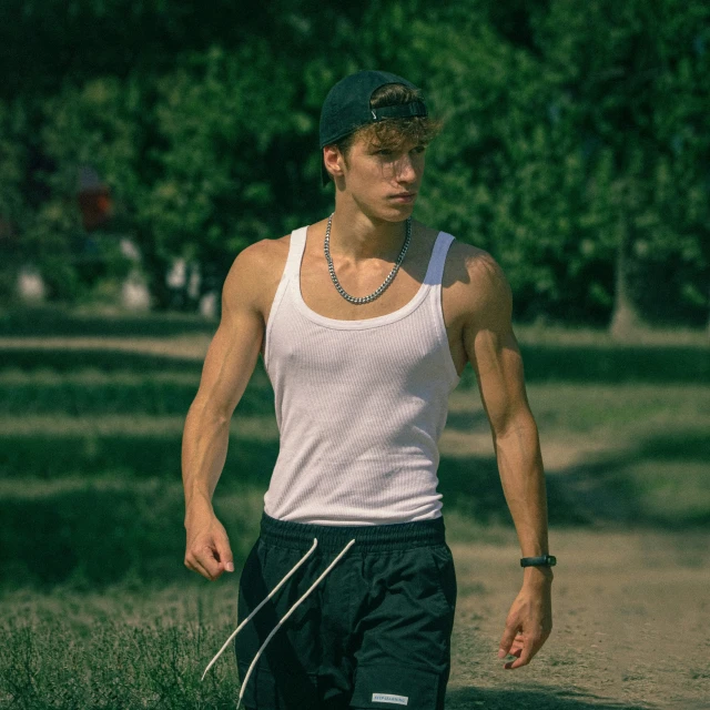 a man wearing a cap walking in a grassy field