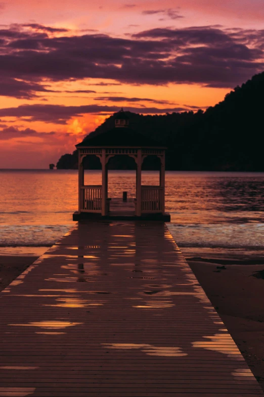 a gazebo sits on a dock next to the ocean