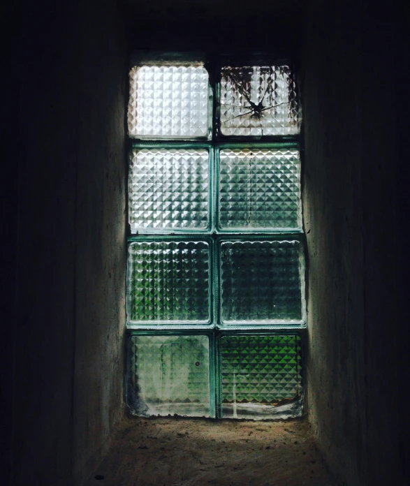 a window with glass coverings behind it in a dark room