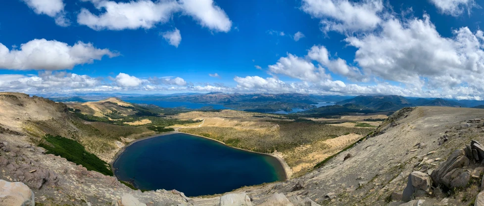 the view from the top of the mountain looking down on a lake and mountains