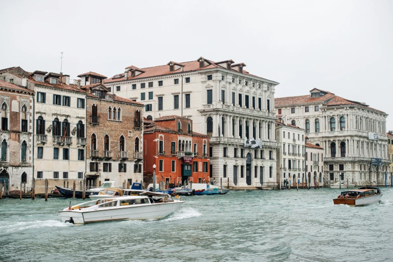 there are several boats in the water and buildings behind them