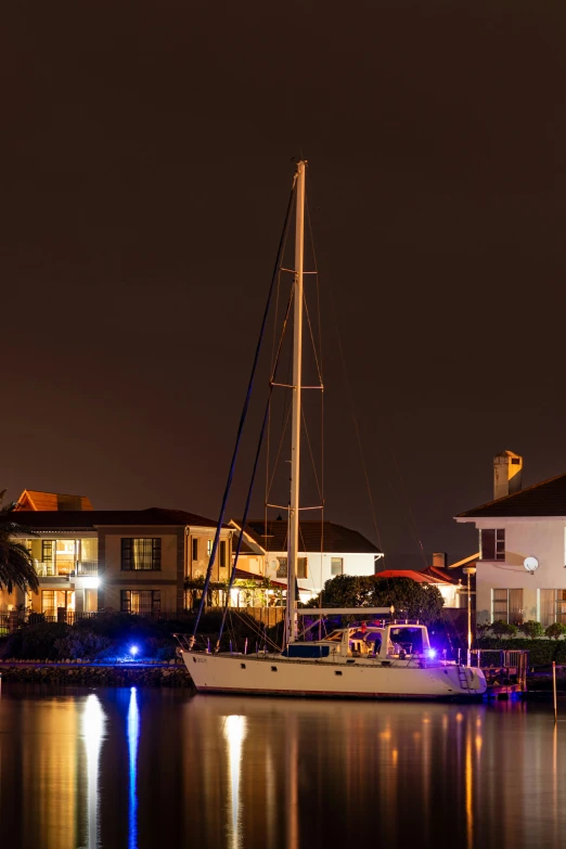 a boat is sitting in the water near a house at night