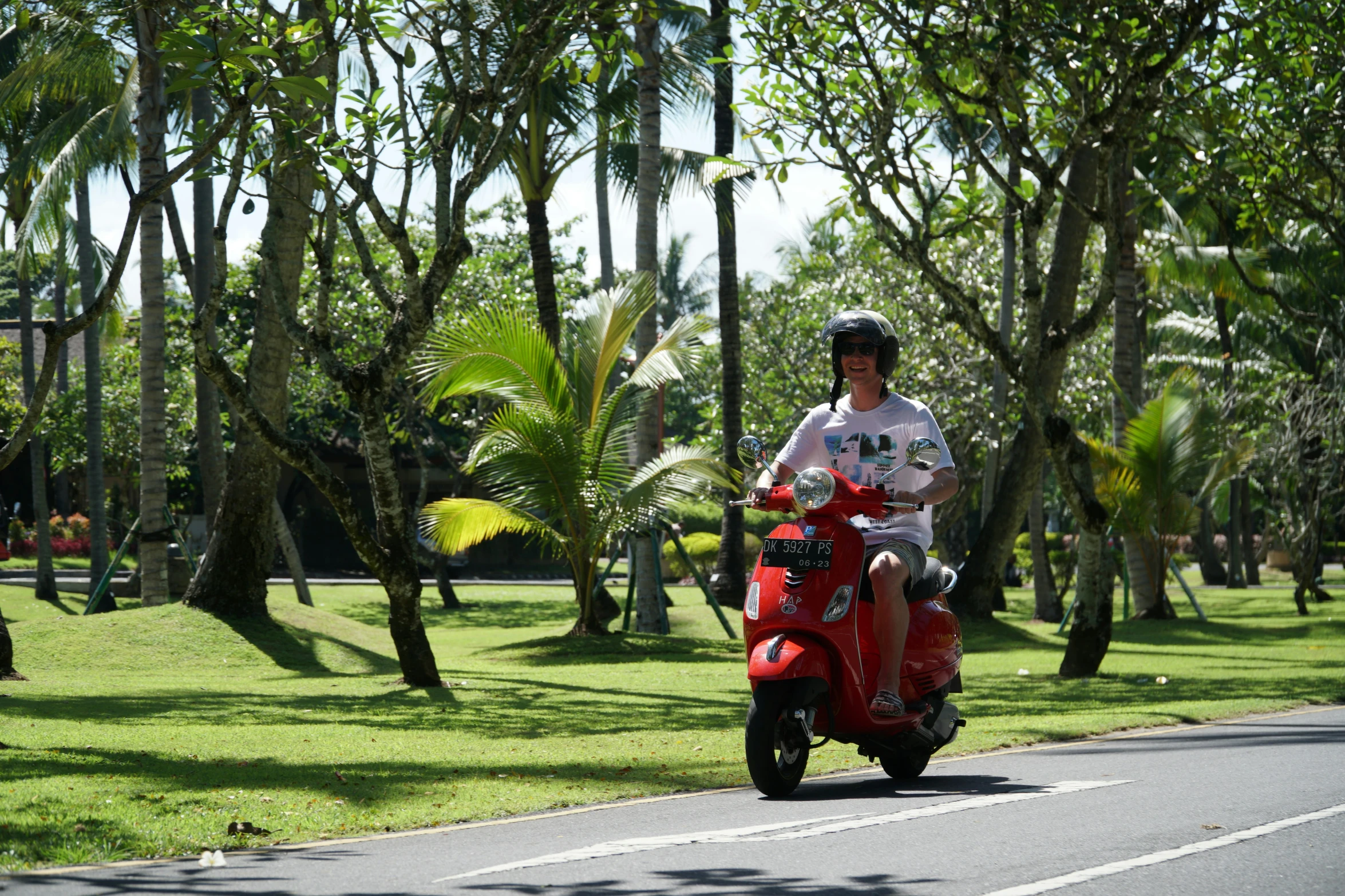 a man rides a motorcycle on a road surrounded by trees