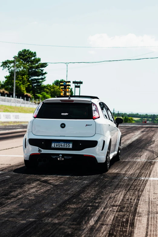 the rear end of a white sport car on a dirt road