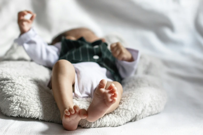 a close up of a baby lying on a bed with white sheets