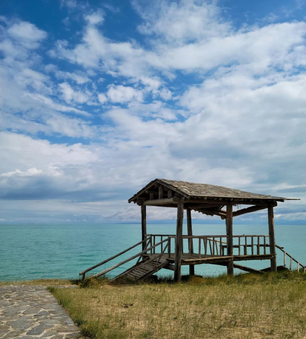 wooden gazebo on top of hill next to ocean