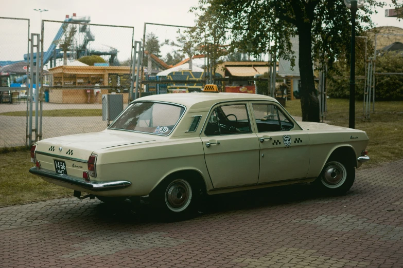 a classic car parked in the street behind a fence