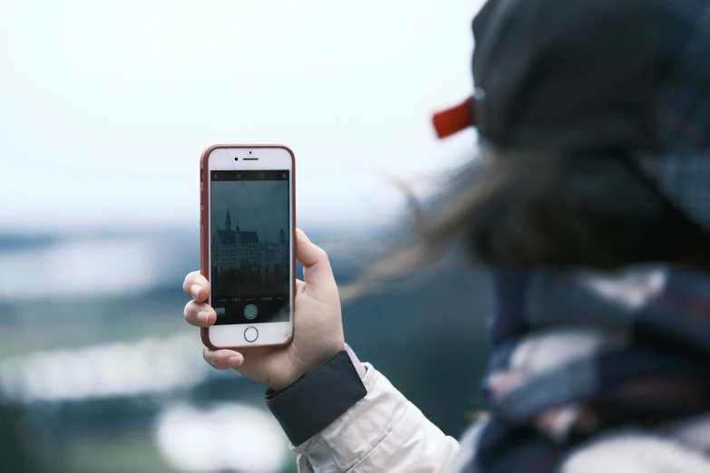 the woman holds up her iphone to take a po