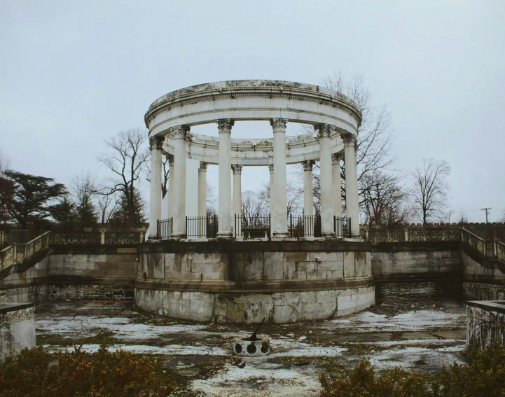 an old circular structure with columns and pillars near a park