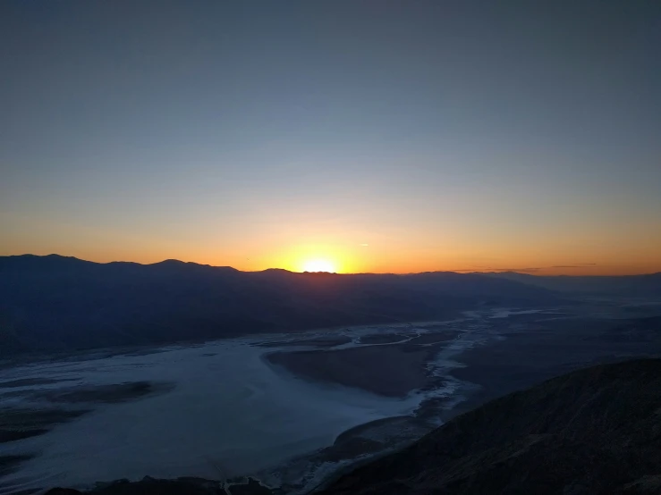 sunset over mountains with river flowing through them