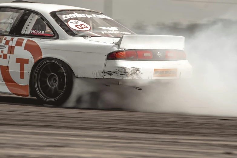 a white race car is kicking up dirt and exhaust