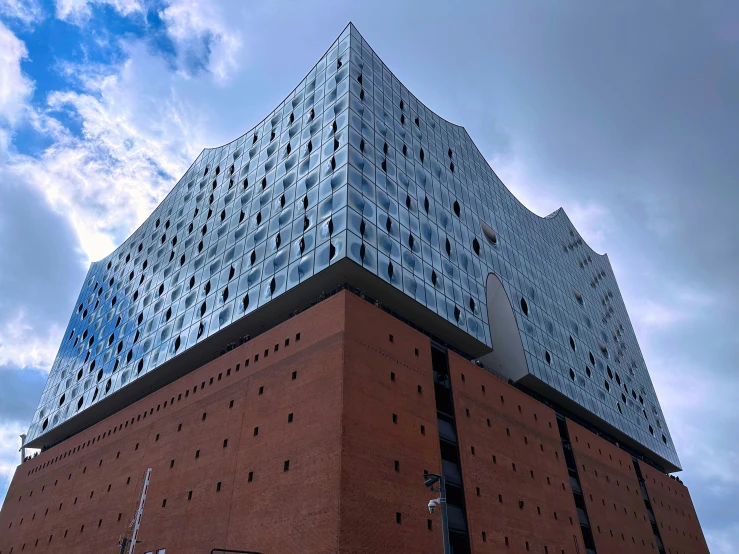 a tall brick building on a corner under a cloudy blue sky