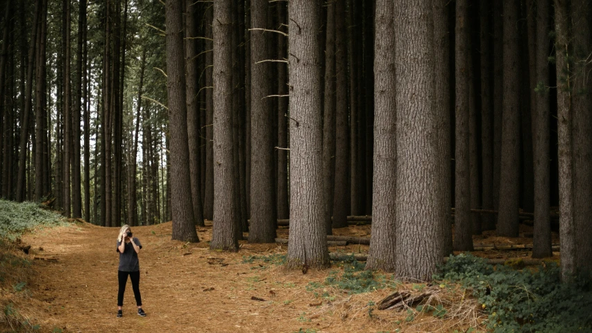 a woman in the woods takes a picture with her camera