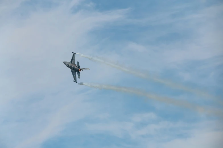 two jets in the air flying through a blue cloudy sky