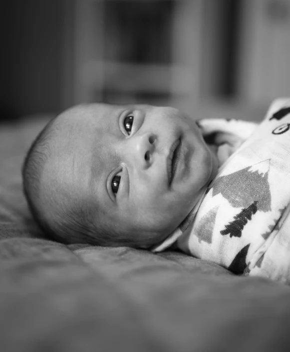 a baby laying on a bed with a blanket