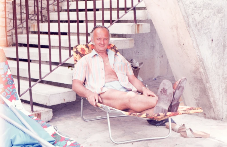 a man sitting on a beach chair with flowers in front of him