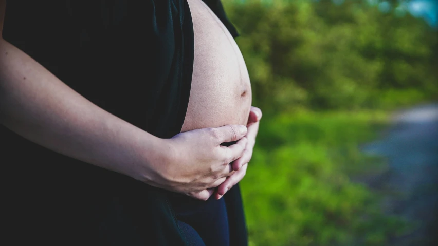 a pregnant woman wearing black clothing holding her stomach