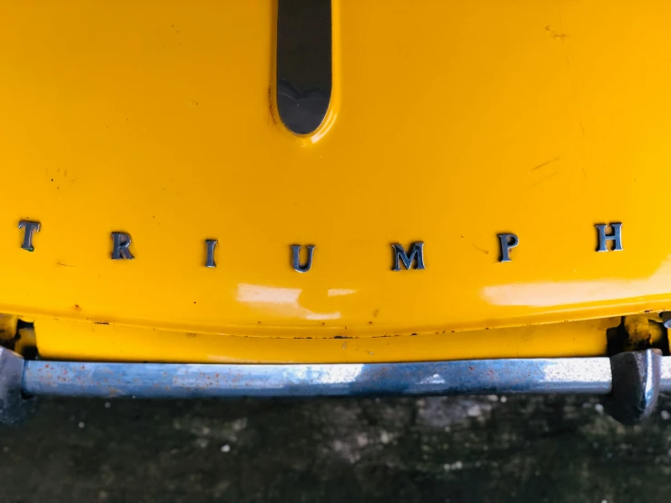 the trunk emblem of a yellow triumph vehicle