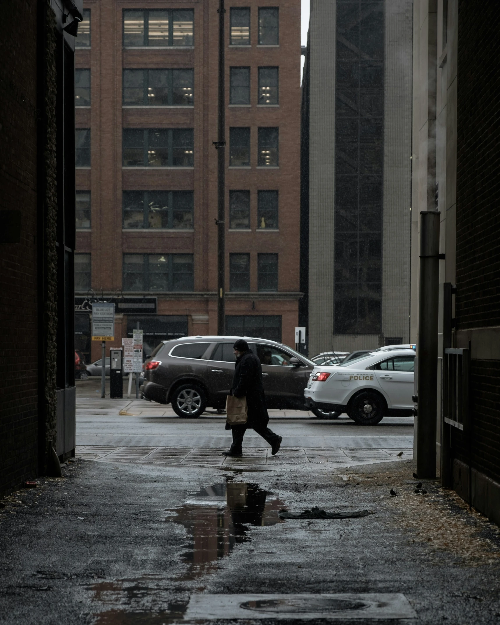 a pedestrian crossing a wet street in the city