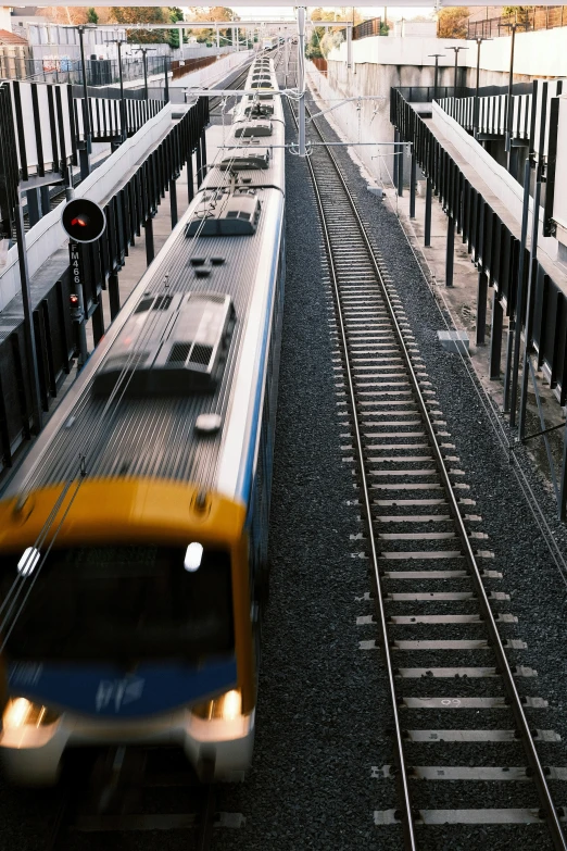 a yellow train traveling down the tracks towards a train stop