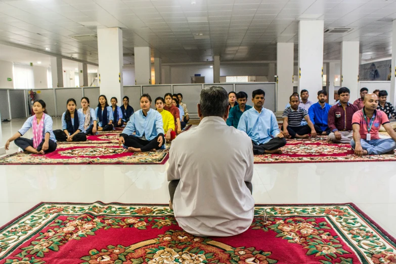 a group of people sitting on mats with their backs turned