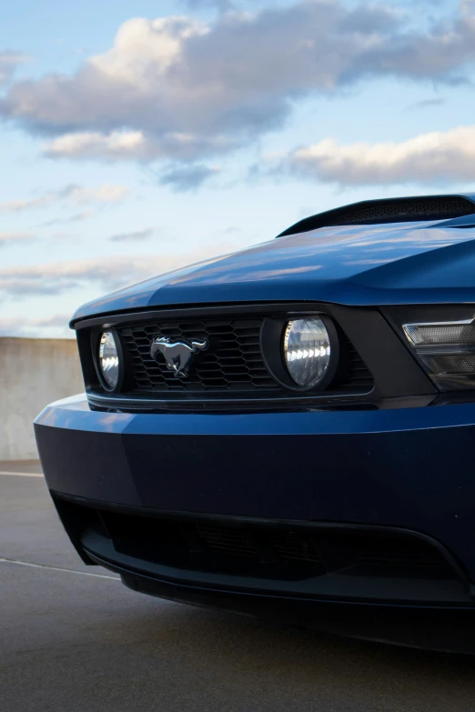 the front end of a blue mustang parked on a concrete parking lot