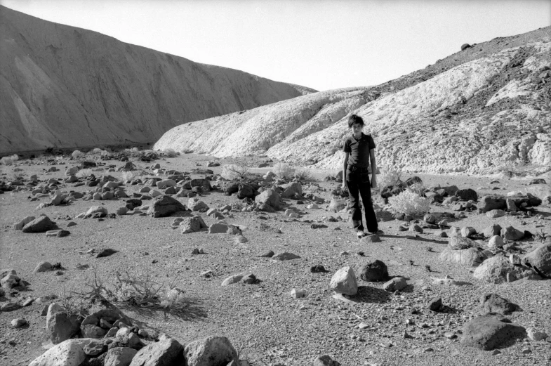 a young man standing alone in the middle of a desert