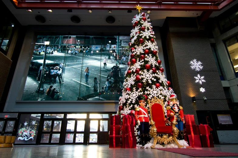 a large christmas tree with lights and snow is in the lobby of a building