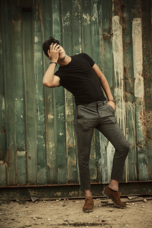 a man leaning against a green painted wall talking on a cellphone