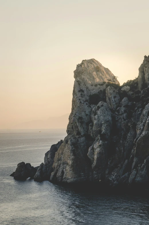 rock island on water in sea near large rocky formations