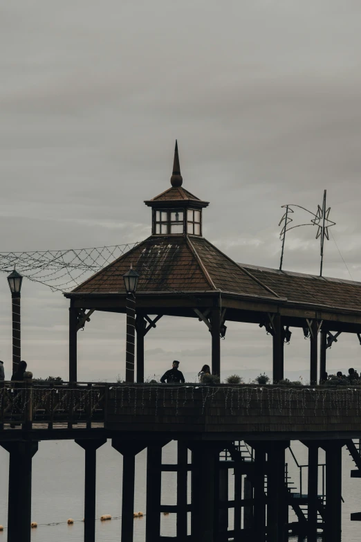 a gazebo is on a pier that has birds flying over it