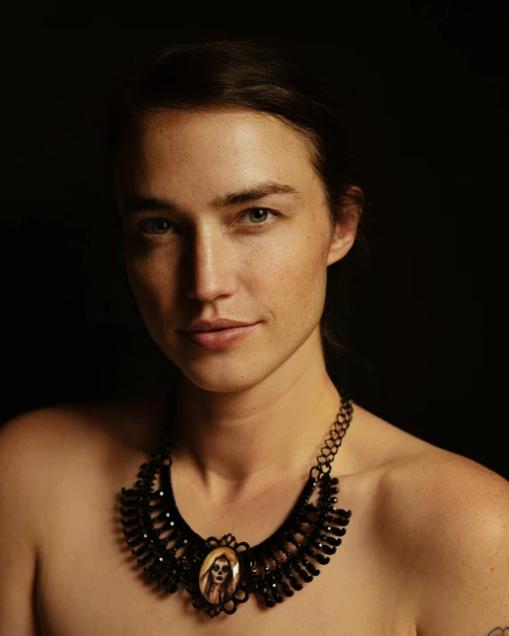 a person in an ornate necklace looks off to the side