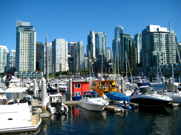 multiple boats are moored in the harbor with skyscrs in the background