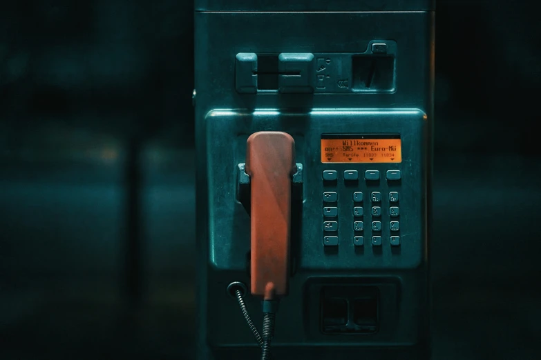 an old public telephone is seen in the dark
