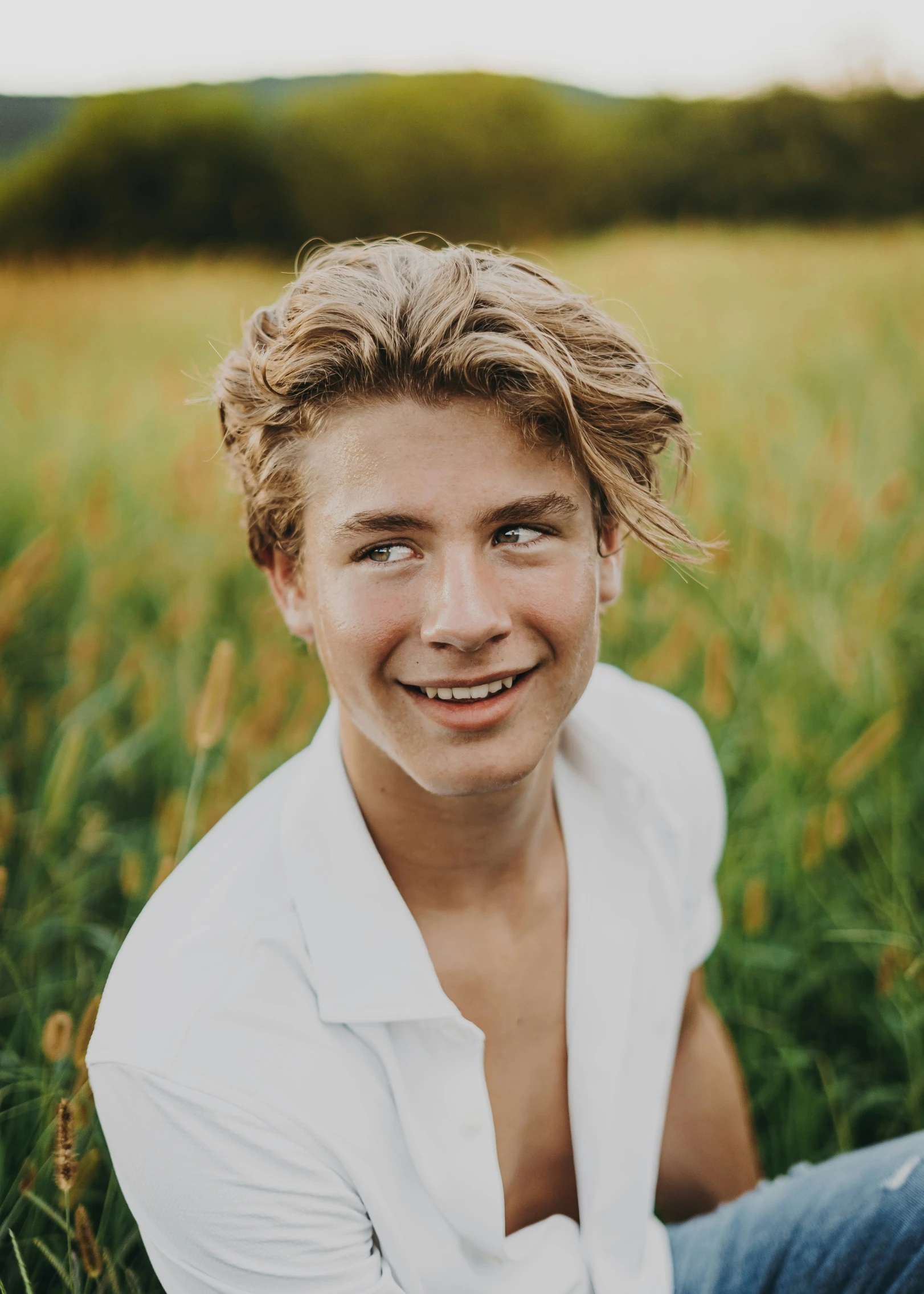 a smiling young man in the middle of a field