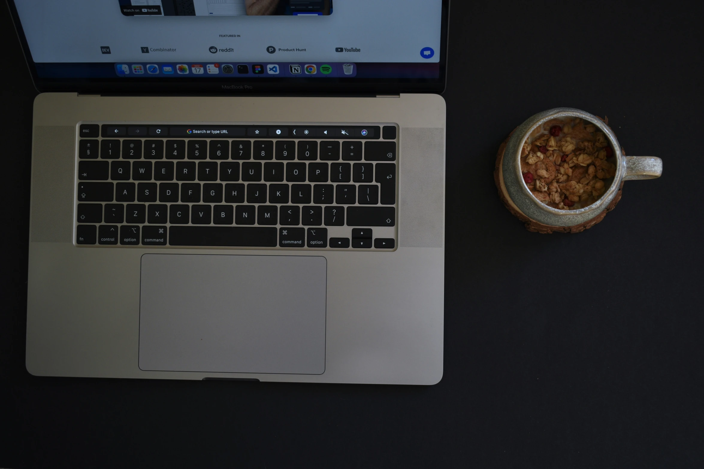 there is a coffee cup and bowl of cereal next to a laptop computer