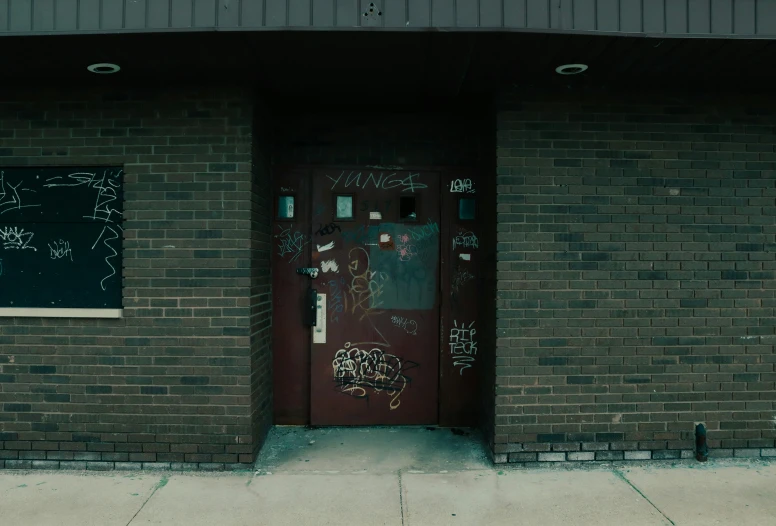 a red door with graffiti on it sitting next to a sidewalk